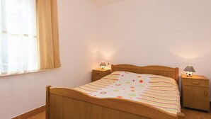 Camera da letto con un letto di legno, due comodini con lampade, una finestra con tende e una parete semplice.