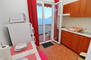 Una cocina compacta con vistas al mar, un pequeño comedor y un balcón con una silla.