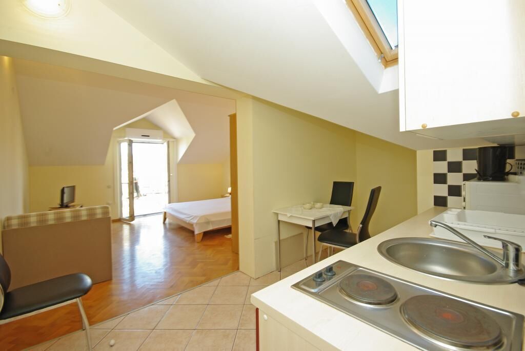 Une pièce compacte comprenant un coin cuisine, un lit, une petite table et une chaise.