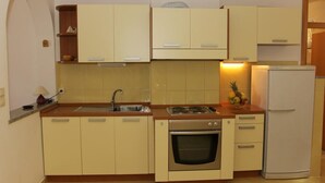 A compact kitchen with a sink, stove, oven, and a refrigerator. - Apartments Villa Muškat - Comfort Two Bedroom Apartment with Terrace (Supetar)