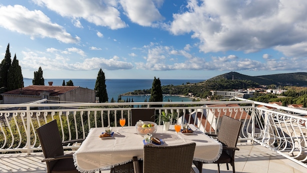 Un balcon avec une table préparée pour le petit-déjeuner, offrant une vue panoramique sur la côte.