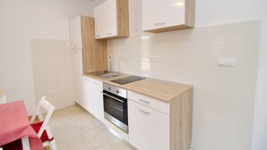 A modern kitchen with white cabinets, a wooden countertop, a stainless steel oven, and a sink.