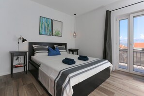 Une chambre moderne avec un grand lit, une table de chevet, une lampe et une vue sur l’extérieur grâce à une porte coulissante.