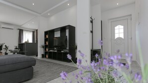 Una sala moderna con un sofá gris, un mueble de entretenimiento negro y una puerta blanca.