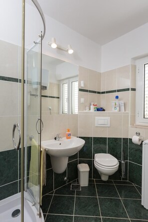 Un baño con ducha de vidrio, lavabo, inodoro y espejo.