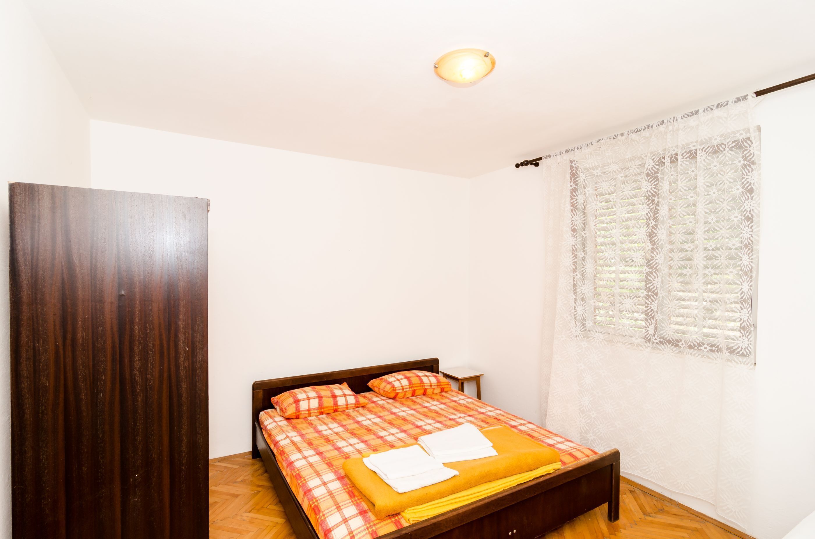 Une chambre à coucher avec un lit, une tête de lit en bois et une fenêtre ornée de rideaux à motifs.