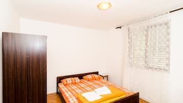 Une chambre à coucher avec un lit, une tête de lit en bois et une fenêtre ornée de rideaux à motifs.
