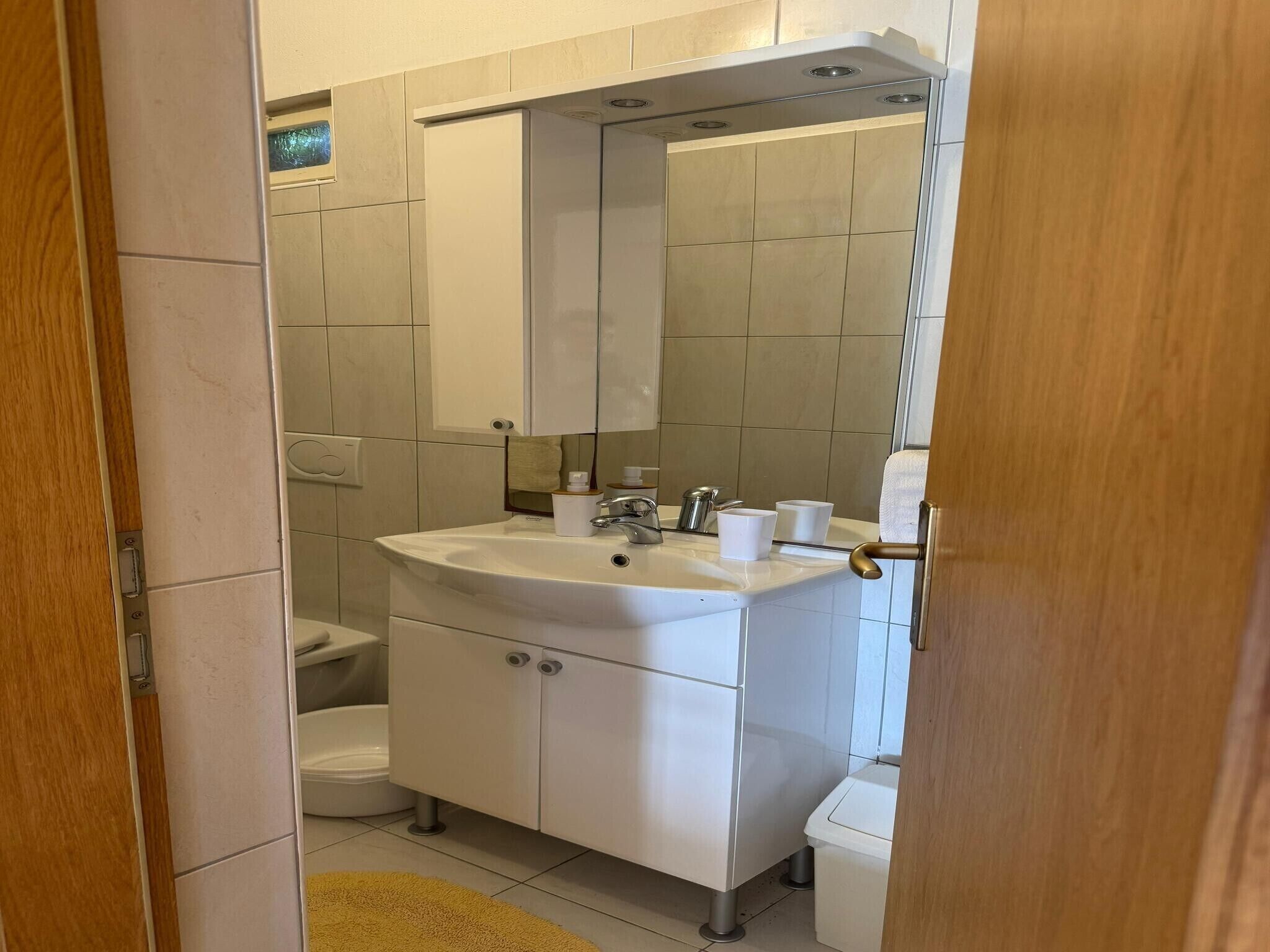 A bathroom with a white sink, mirror, and toilet.
