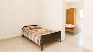 A small, single-bed room with a wooden bed frame, a plain white wall, and a small window. - Apartmetns Franka Saplunara-One-Bedroom Apartment with Terrace and Sea View No2 (Saplunara)