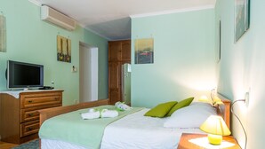 Ein Schlafzimmer mit einem Bett, einem Nachttisch, einer Lampe und einem Fernseher auf einer Kommode.