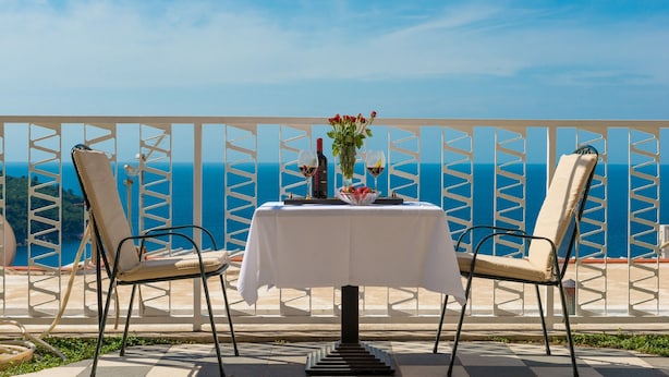 Ein Tisch für zwei mit Meerblick, eine weiße Tischdecke und eine Weinflasche.