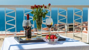 Ein Tisch mit einer Weinflasche, einem Weinglas, einer Vase mit roten Rosen und einer Schale Erdbeeren.