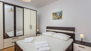 A bedroom with a bed, a wardrobe, a nightstand, and a painting on the wall.