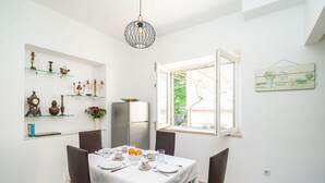 Un coin repas avec une table dressée pour quatre personnes, un réfrigérateur et des objets décoratifs disposés sur des étagères.