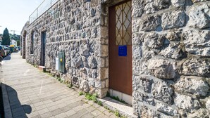 Un bâtiment en pierre avec une porte marron et une enseigne bleue.