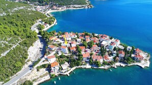 An aerial view of a coastal village with houses, a winding road, and clear blue waters. - Apartments Mediterranean House - Two Bedroom Apartment with Terrace (Klek)