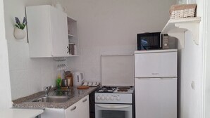 A compact kitchen with white cabinets, a stove, a microwave, and a sink. - Apartments Mediterranean House - Two Bedroom Apartment with Terrace (Klek)