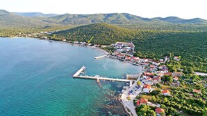 An aerial view of a coastal town with a marina, houses, and surrounding hills.