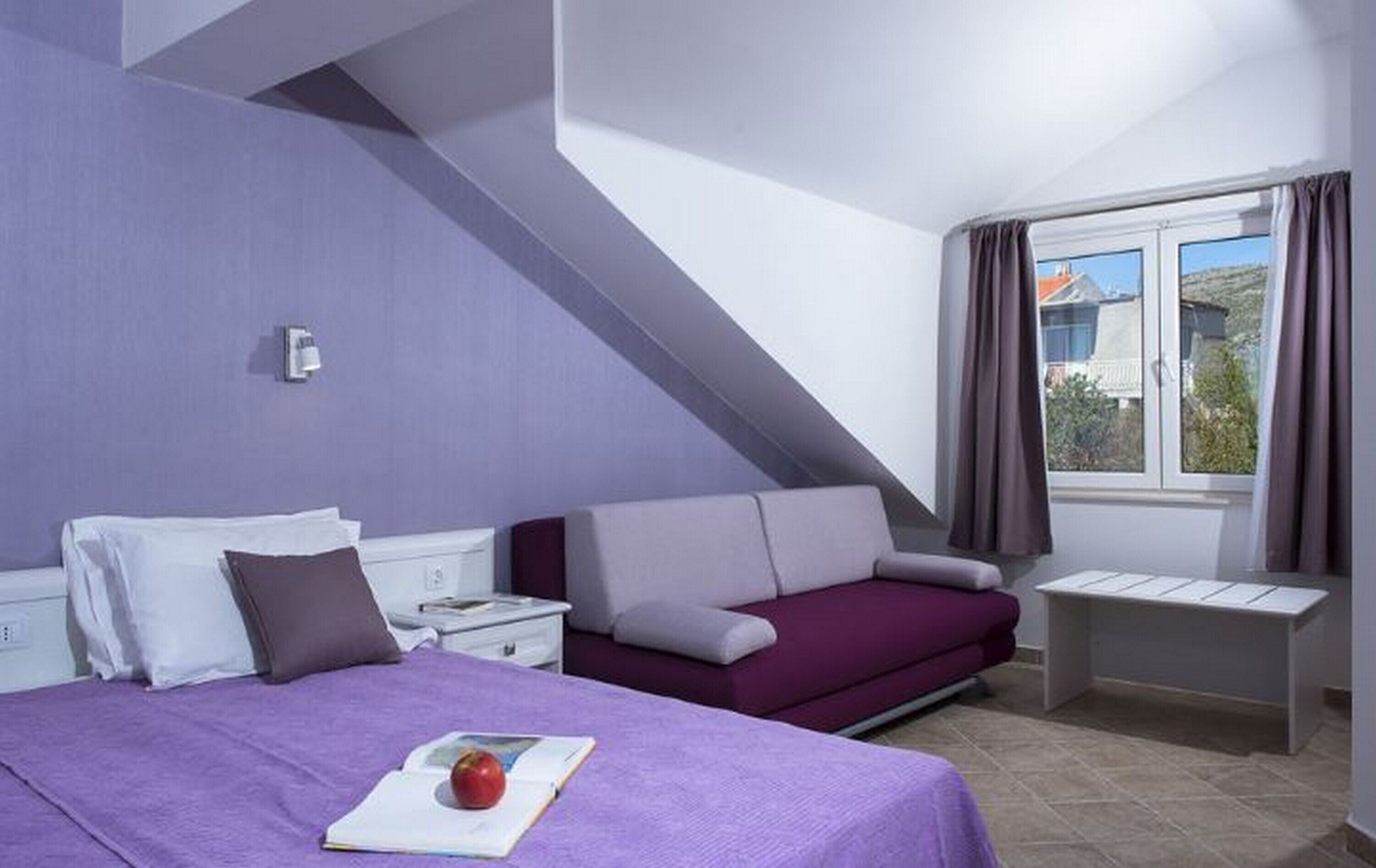 Ein Schlafzimmer mit Bett, Nachttisch, Sofa und einem Fenster mit Vorhängen.