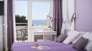 Une chambre Ă coucher avec un lit, un bureau et une chaise. La fenĂŞtre offre une vue sur la mer.