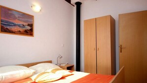 A bedroom with a bed, a nightstand, a wooden wardrobe, and a painting on the wall.