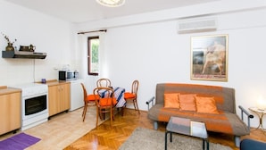 Un espace de vie compact comprenant un coin cuisine, un canapé, une table à manger avec des chaises et un tableau encadré au mur.