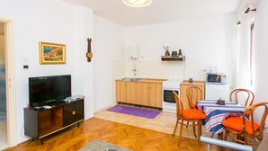 Un espace de vie compact comprenant un coin cuisine, un coin repas et un téléviseur.