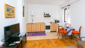 Un espace de vie compact comprenant une kitchenette, un coin repas et un téléviseur.