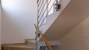 Un escalier dont les marches sont recouvertes d’une moquette beige, avec une main courante en bois et des rampes en métal.