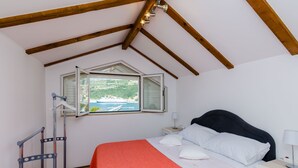 Ein Schlafzimmer mit Bett, Nachttisch, Fenster mit Blick auf ein Gewässer und Holzboden.