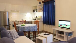 Ein kompakter Wohnraum mit Essbereich, Küche und Fernseher.