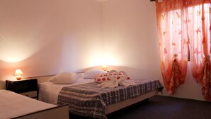 Ein Schlafzimmer mit einem Bett, zwei Nachttischen, einer Lampe und einem Fenster mit Vorhängen.