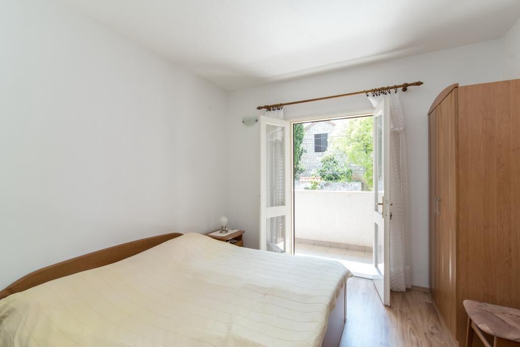 Ein Schlafzimmer mit einem Bett, einem Holzschrank und einer Tür, die auf einen Balkon führt.