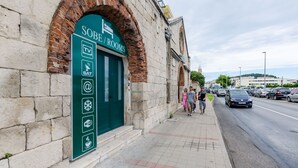 Un edificio con un letrero que indica 'SOBE/ROOMS' y ofrece servicios como TV, satélite, Wi-Fi y una cafetería.