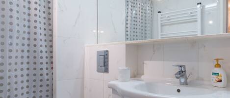 A bathroom with a toilet, sink, and shower.