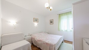 A bedroom with a bed, a bedside table, a wardrobe, and a window with curtains. - Apartments Magdalena - Apartment with Sea View and Terrace (A3) (Bol)