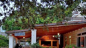 Une entrée dallée de pierres, agrémentée d’une pergola en bois et d’un mur en briques.
