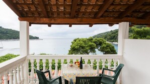Un balcon avec une table dressée pour deux personnes, donnant sur une étendue d’eau et une végétation luxuriante.