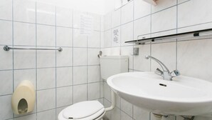 Une petite salle de bain propre, équipée de toilettes, d’un lavabo et d’un sèche-mains.