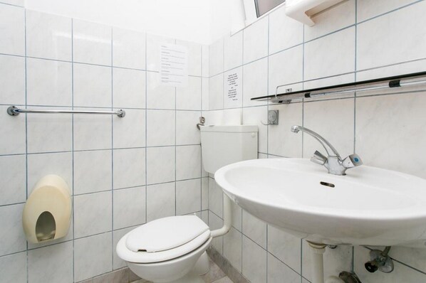 A small, clean bathroom with a toilet, sink, and hand dryer.