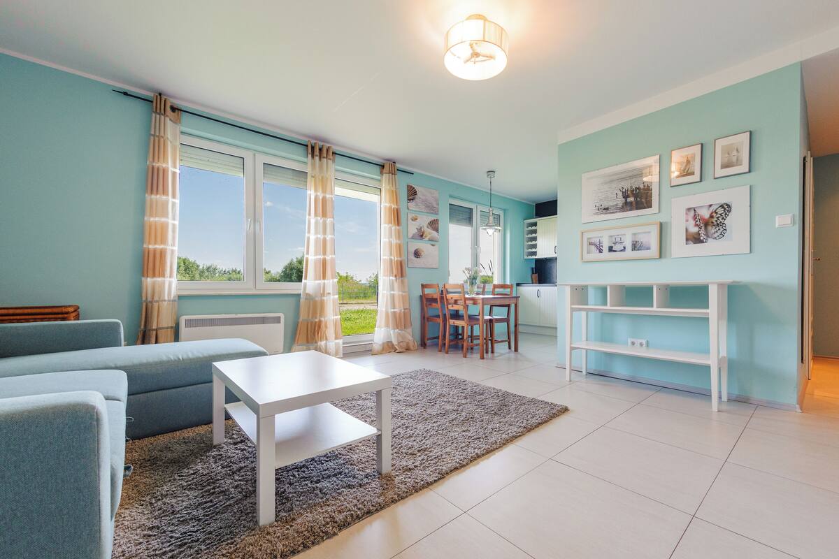 Ein modernes Wohnzimmer mit einer Couch, einem Esstisch und einer Küchenzeile mit einem weißen Schrank.