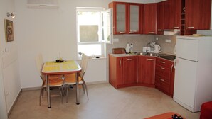 Une cuisine de taille réduite, dotée de meubles en bois, d’un réfrigérateur blanc et d’une table à manger avec des chaises.