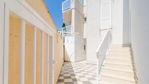 A narrow corridor with checkered flooring, white walls, and a staircase with white railings. - Apartment Riki - Studio Apartment with Balcony and City View (Dubrovnik)