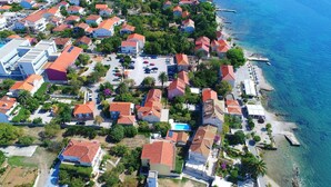 An aerial view of a coastal residential area with houses, a beach, and a pier.