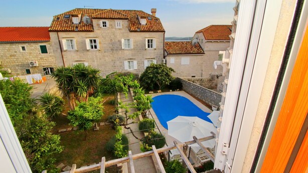 A courtyard with a swimming pool, stone buildings, and a view of the surrounding area.