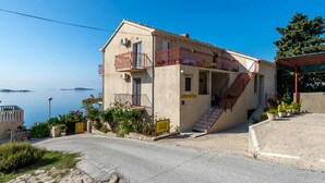 A two-story building with a balcony, a staircase, and a view of the sea.