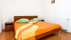 A bedroom with a wooden bed, two nightstands, a lamp on each, and a radiator.