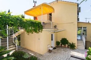 A small, single-story building with a balcony and a yellow awning.
