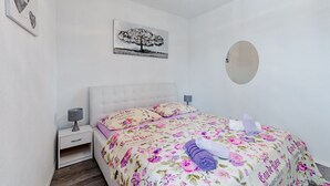 Ett sovrum med en säng, två sängbord, en lampa, en spegel och en tavla på väggen.