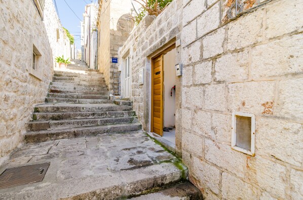 A narrow stone staircase leading to a building with a wooden door and a small window.